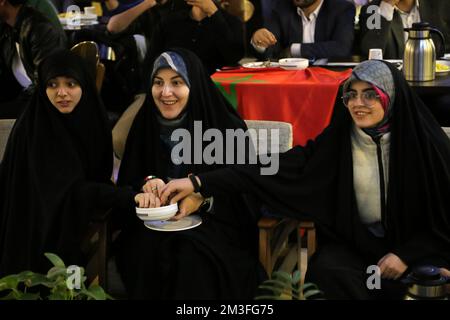 Teheran, Teheran, Iran. 14.. Dezember 2022. Getarnte iranische Fans reagieren auf das Halbfinale der FIFA-Weltmeisterschaft Katar 2022 zwischen Frankreich und Marokko im Nakhlestan Café im Zentrum von Teheran, Iran, am 14. Dezember 2022. Fans aus dem Iran, dem Libanon, dem Jemen, Syrien und Palästina versammeln sich im Nakhlestan Cafe, das vom Owj, der Arts and Media Organization des Islamic Revolutionary Guard Corps (IRGS), betrieben wird und sich im Besitz der Organisation für Kunst und Medien befindet, um die marokkanische Nationalmannschaft zu unterstützen. Nach dem Sieg gegen Portugal in Katar am 10.. Dezember trugen die Marokkaner palästinensische Flaggen, um ihre Unterstützung für Pale zu zeigen Stockfoto