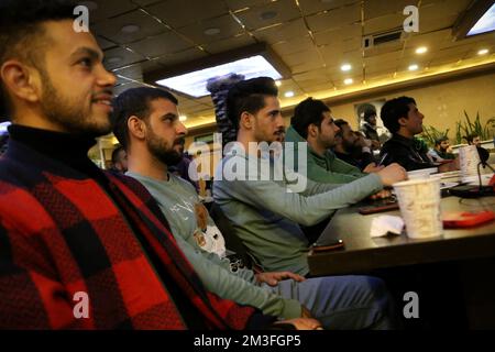 Teheran, Teheran, Iran. 14.. Dezember 2022. Fußballfans aus Palästina, Syrien, dem Libanon, dem Jemen und dem Libanon, Sehen Sie sich das Halbfinale der FIFA-Weltmeisterschaft Katar 2022 zwischen Frankreich und Marokko im Nakhlestan Café im Zentrum von Teheran, Iran, am 14. Dezember 2022 an. Fans aus dem Iran, dem Libanon, dem Jemen, Syrien und Palästina versammeln sich im Nakhlestan Cafe, das vom Owj, der Arts and Media Organization des Islamic Revolutionary Guard Corps (IRGS), betrieben wird und sich im Besitz der Organisation für Kunst und Medien befindet, um die marokkanische Nationalmannschaft zu unterstützen. Nach dem Sieg gegen Portugal in Katar am 10.. Dezember trugen die Marokkaner palästinensische Flaggen Stockfoto