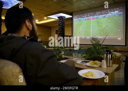 Teheran, Teheran, Iran. 14.. Dezember 2022. Ein iranischer Mann sieht am 14. Dezember 2022 im Nakhlestan Café in der Innenstadt von Teheran, Iran, eine Live-Übertragung des Halbfinalspiels der Katar-Weltmeisterschaft 2022 zwischen Marokko und Frankreich. Fans aus dem Iran, dem Libanon, dem Jemen, Syrien und Palästina versammeln sich im Nakhlestan Cafe, das vom Owj, der Arts and Media Organization des Islamic Revolutionary Guard Corps (IRGS), betrieben wird und sich im Besitz der Organisation für Kunst und Medien befindet, um die marokkanische Nationalmannschaft zu unterstützen. Nach dem Sieg gegen Portugal in Katar am 10.. Dezember trugen die Marokkaner palästinensische Flaggen, um ihre Unterstützung für die Palästinenser zu zeigen. Fra Stockfoto