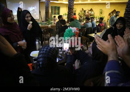 Teheran, Teheran, Iran. 14.. Dezember 2022. Die Iraner versammeln sich am 14. Dezember 2022 im Nakhlestan Café in der Innenstadt von Teheran, Iran, um eine Live-Übertragung des Halbfinalspiels der Katar-Weltmeisterschaft 2022 zwischen Marokko und Frankreich zu sehen. Fans aus dem Iran, dem Libanon, dem Jemen, Syrien und Palästina versammeln sich im Nakhlestan Cafe, das vom Owj, der Arts and Media Organization des Islamic Revolutionary Guard Corps (IRGS), betrieben wird und sich im Besitz der Organisation für Kunst und Medien befindet, um die marokkanische Nationalmannschaft zu unterstützen. Nach dem Sieg gegen Portugal in Katar am 10.. Dezember trugen die Marokkaner palästinensische Flaggen, um ihre Unterstützung für die Palästinenser zu zeigen. F Stockfoto