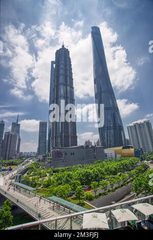 Shanghai World Financial Center, Shanghai Tower, Jin Mao Tower und urbaner Dschungel fotografiert von unten im Sommer vor blauem Himmel und Wolken Stockfoto