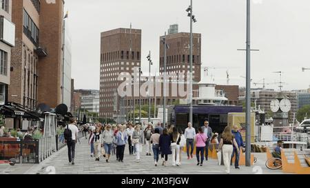 Norwegen, Oslo - 27. Juli 2022: Überfüllte Stadtstraße an einem Sommertag. Aktion. Menschen, die an Gebäuden entlang gehen Stockfoto