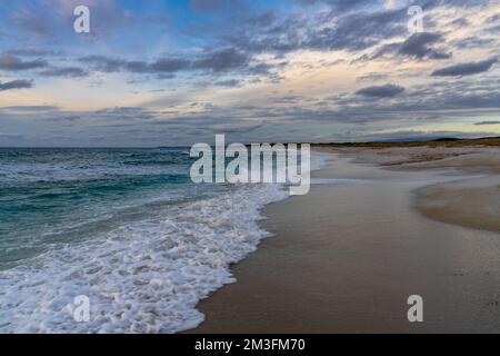 Ein leerer weißer Sandstrand und Sanddünen bei Sonnenuntergang mit türkisfarbenem Wasser auf Sardinien Stockfoto