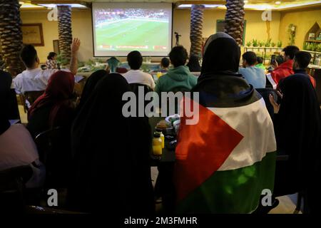 Teheran, Teheran, Iran. 15.. Dezember 2022. Ein iranischer Fan, der eine palästinensische Flagge trug, während er das Nakhlestan Café in der Innenstadt von Teheran besuchte, weil er das Halbfinale der FIFA-Weltmeisterschaft Katar 2022 zwischen Frankreich und Marokko am 15. Dezember 2022 auf der Leinwand gesehen hat. Fans aus dem Iran, dem Libanon, dem Jemen, Syrien und Palästina versammeln sich im Nakhlestan Cafe, das vom Owj, der Arts and Media Organization des Islamic Revolutionary Guard Corps (IRGS), betrieben wird und sich im Besitz der Organisation für Kunst und Medien befindet, um die marokkanische Nationalmannschaft zu unterstützen. Nach dem Sieg gegen Portugal in Katar am 10.. Dezember trugen die Marokkaner palästinensische Flaggen, um ihre Unterstützung zu zeigen Stockfoto