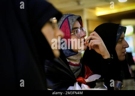 Teheran, Teheran, Iran. 15.. Dezember 2022. Getarnte iranische Fans reagieren auf das Halbfinale der FIFA-Weltmeisterschaft Katar 2022 zwischen Frankreich und Marokko im Nakhlestan Café im Zentrum von Teheran, Iran, am 15. Dezember 2022. Fans aus dem Iran, dem Libanon, dem Jemen, Syrien und Palästina versammeln sich im Nakhlestan Cafe, das vom Owj, der Arts and Media Organization des Islamic Revolutionary Guard Corps (IRGS), betrieben wird und sich im Besitz der Organisation für Kunst und Medien befindet, um die marokkanische Nationalmannschaft zu unterstützen. Nach dem Sieg gegen Portugal in Katar am 10.. Dezember trugen die Marokkaner palästinensische Flaggen, um ihre Unterstützung für Pale zu zeigen Stockfoto