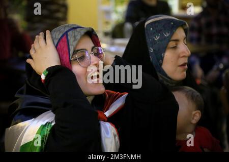 Teheran, Teheran, Iran. 15.. Dezember 2022. Getarnte iranische Fans reagieren auf das Halbfinale der FIFA-Weltmeisterschaft Katar 2022 zwischen Frankreich und Marokko im Nakhlestan Café im Zentrum von Teheran, Iran, am 15. Dezember 2022. Fans aus dem Iran, dem Libanon, dem Jemen, Syrien und Palästina versammeln sich im Nakhlestan Cafe, das vom Owj, der Arts and Media Organization des Islamic Revolutionary Guard Corps (IRGS), betrieben wird und sich im Besitz der Organisation für Kunst und Medien befindet, um die marokkanische Nationalmannschaft zu unterstützen. Nach dem Sieg gegen Portugal in Katar am 10.. Dezember trugen die Marokkaner palästinensische Flaggen, um ihre Unterstützung für Pale zu zeigen Stockfoto