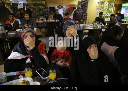 Teheran, Teheran, Iran. 15.. Dezember 2022. Getarnte iranische Fans reagieren auf das Halbfinale der FIFA-Weltmeisterschaft Katar 2022 zwischen Frankreich und Marokko im Nakhlestan Café im Zentrum von Teheran, Iran, am 15. Dezember 2022. Fans aus dem Iran, dem Libanon, dem Jemen, Syrien und Palästina versammeln sich im Nakhlestan Cafe, das vom Owj, der Arts and Media Organization des Islamic Revolutionary Guard Corps (IRGS), betrieben wird und sich im Besitz der Organisation für Kunst und Medien befindet, um die marokkanische Nationalmannschaft zu unterstützen. Nach dem Sieg gegen Portugal in Katar am 10.. Dezember trugen die Marokkaner palästinensische Flaggen, um ihre Unterstützung für Pale zu zeigen Stockfoto