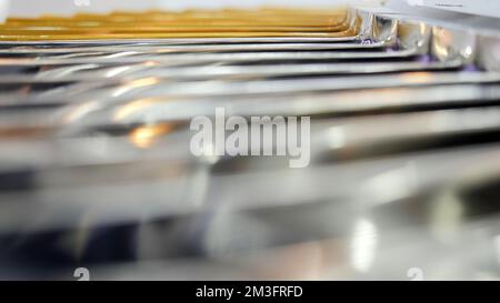 Nahaufnahme von verschwommenen parallelen Balken aus Metall mit blinkenden kleinen Glühbirnen. Medien. Industrieller Hintergrund mit einem Teil der Maschine Stockfoto