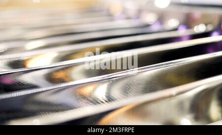 Nahaufnahme von verschwommenen parallelen Balken aus Metall mit blinkenden kleinen Glühbirnen. Medien. Industrieller Hintergrund mit einem Teil der Maschine Stockfoto