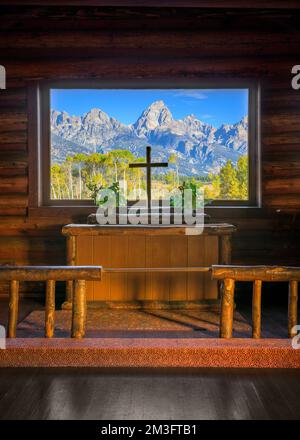 Berge durch Glasfenster über dem Altar der historischen Kapelle der Transfiguration im Grand Teton National Park in der Nähe von Moose, Wyoming Stockfoto