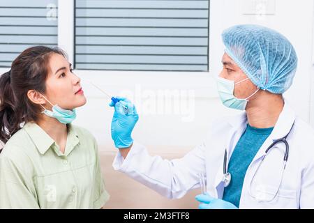 Doktor man nehmen Speichelprobe durch die Nase mit Wattestäbchen, um Coronavirus-Test von einer jungen asiatischen Frau zu überprüfen Stockfoto