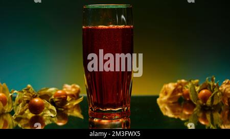 Nahaufnahme des Glases auf dem Tisch mit rotem Limonadengetränk. Clip. Die Bar ist mit Beeren dekoriert und mit unscharfen Lichtern dekoriert Stockfoto