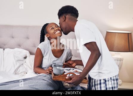 Ich möchte, dass du dich heute besonders fühlst. Ein junger Mann bringt seiner Freundin Frühstück ins Bett. Stockfoto