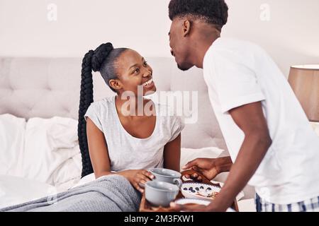 Alles für die schönste Frau, die ich kenne. Ein junger Mann bringt seiner Freundin Frühstück ins Bett. Stockfoto