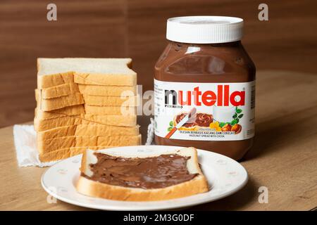 Nutella mit großen und kleinen Flaschen und etwas Weißbrot ordentlich auf dem Esstisch angeordnet Stockfoto