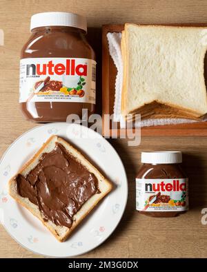 Nutella mit großen und kleinen Flaschen und etwas Weißbrot ordentlich auf dem Esstisch angeordnet Stockfoto