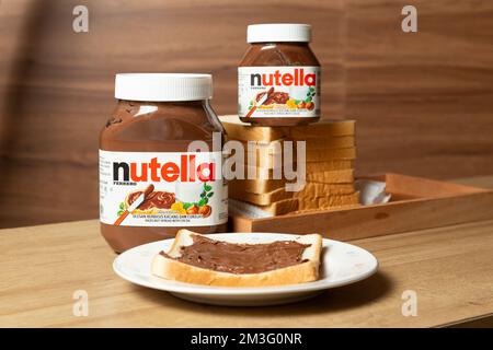 Nutella mit großen und kleinen Flaschen und etwas Weißbrot ordentlich auf dem Esstisch angeordnet Stockfoto