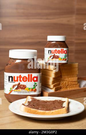 Nutella mit großen und kleinen Flaschen und etwas Weißbrot ordentlich auf dem Esstisch angeordnet Stockfoto