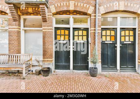 Zwei schwarze Türen vor einem roten Backsteingebäude mit weißen Verzierungen um die Türen und Fensterscheiben Stockfoto