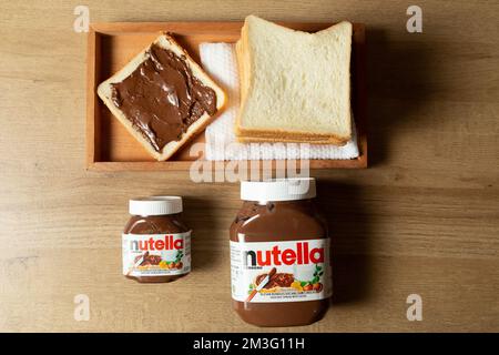 Nutella mit großen und kleinen Flaschen und etwas Weißbrot ordentlich auf dem Esstisch angeordnet Stockfoto