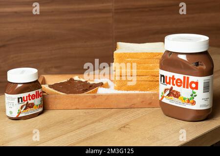 Nutella mit großen und kleinen Flaschen und etwas Weißbrot ordentlich auf dem Esstisch angeordnet Stockfoto