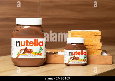 Nutella mit großen und kleinen Flaschen und etwas Weißbrot ordentlich auf dem Esstisch angeordnet Stockfoto