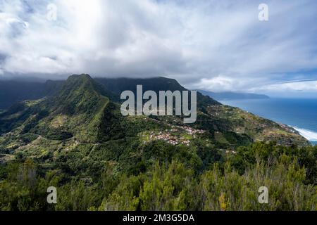Kamm von Pico do Alto, Blick auf bewaldete, wolkenbedeckte Berge mit dem Dorf Boaventura, Madeira, Portugal Stockfoto