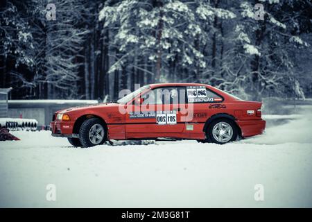 12-12-2022 Riga, Lettland ein rotes Auto parkt im Schnee in der Nähe eines Waldes mit einem Schild auf der Seite mit der Aufschrift „Schneemobil“. . Stockfoto