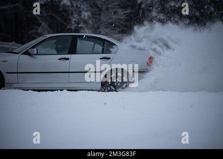 12-12-2022 Riga, Lettland im Winter fährt ein weißes Auto durch den Schnee. . Stockfoto