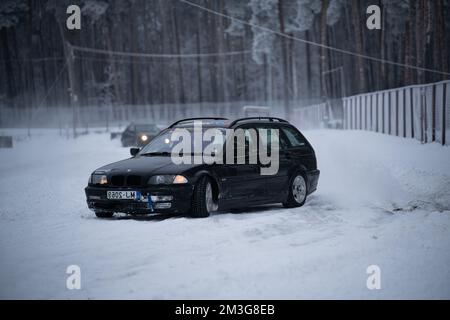 12-12-2022 Riga, Lettland ein Auto steht im Schnee neben einem Zaun und Bäumen im Hintergrund. . Stockfoto