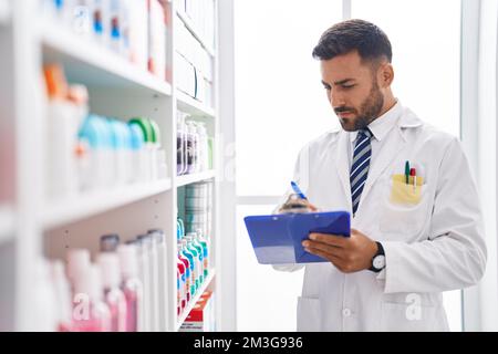 Junger hispanischer Apotheker, der auf einem Dokument in der Apotheke schreibt Stockfoto