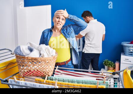 Hispanische Mutter und Sohn hängen Kleidung an der Wäscheleine gestresst und frustriert mit Hand auf Kopf, überrascht und wütend Gesicht Stockfoto