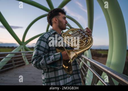 Ein Musiker, der mit seinem Horn in der Hand auf einer Brücke läuft. Stockfoto