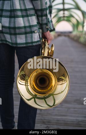 Ein Musiker, der mit seinem Horn in der Hand auf einer Brücke läuft. Stockfoto