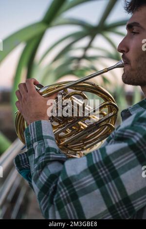 Ein Musiker, der mit seinem Horn in der Hand auf einer Brücke läuft. Stockfoto