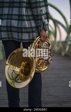 Ein Musiker, der mit seinem Horn in der Hand auf einer Brücke läuft. Stockfoto