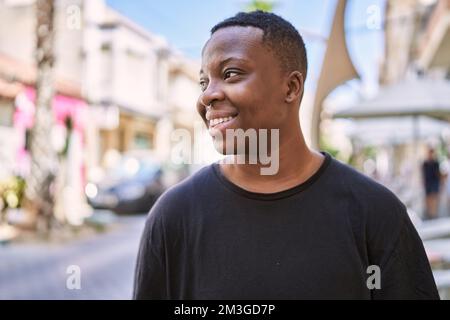 Junge afroamerikanische Transgender lächelt selbstbewusst auf der Straße Stockfoto