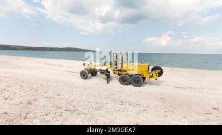 Baustelle für Bulldozer. Schuss. Draufsicht auf Bulldozer, die auf dem Meer am Strand fahren. Sandbergbau oder Baustelle an der Küste. Stockfoto