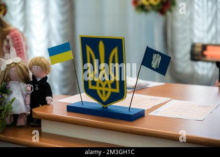 Ukrainische Flagge und Wappen mit Stoff mit verpixelter Tarnung. Tuch mit Camouflaster in grauen und grünen Pixelformen mit ukrainischem Muster Stockfoto