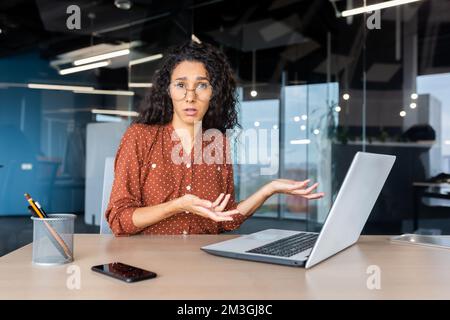Frustrierte und traurige Frau im Büro, die in die Kamera schaut, Geschäftsfrau unzufrieden mit den erzielten Ergebnissen, die am Schreibtisch mit einem Notebook bei der Arbeit gearbeitet hat. Stockfoto