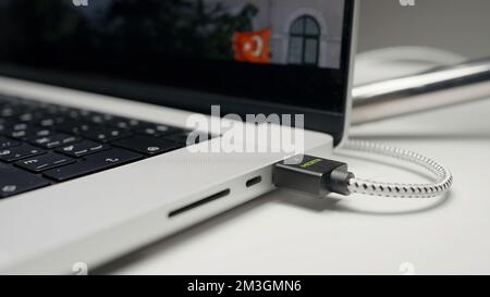 Nahaufnahme des USB-Flashlaufwerks, das in den Anschluss an der Seite eines Laptops eingesteckt wird. Aktion. Teil eines Laptops mit Bildschirm und Film Stockfoto