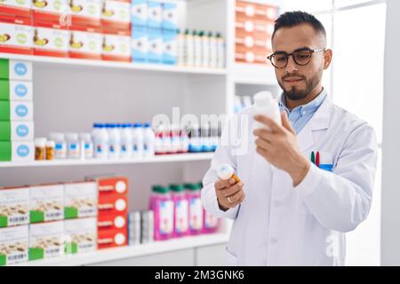 Junger hispanic-Mann Apotheker hält Pillen Flaschen in der Apotheke Stockfoto