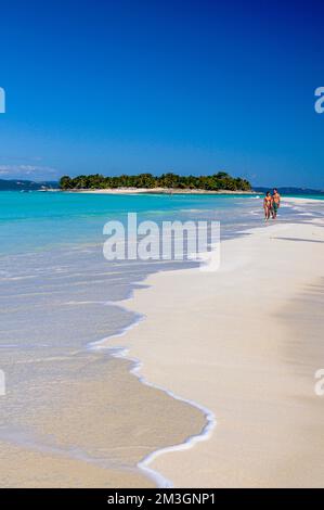 Ein Paar, das auf einem weißen Sandstrand auf der Insel Nosy Iranja in der Nähe von Nosy Be, Madagaskar spaziert Stockfoto