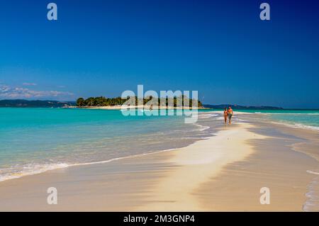 Ein Paar, das auf einem weißen Sandstrand auf der Insel Nosy Iranja in der Nähe von Nosy Be, Madagaskar spaziert Stockfoto