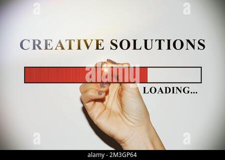 Frauenhand mit glitzernden Nägeln, die die Ladeleiste mit dem Text „Creative Solution“ zeigt Stockfoto