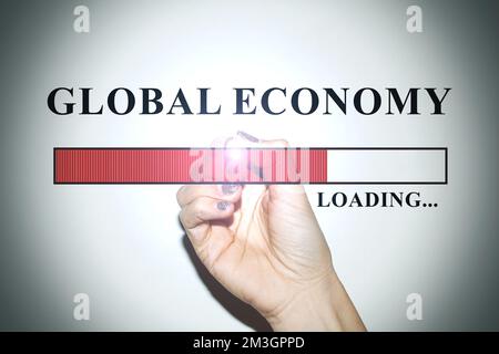 Hand einer Geschäftsfrau mit glitzernden Nägeln, die die Ladeleiste mit dem Text „Global Economy“ zeigt Stockfoto