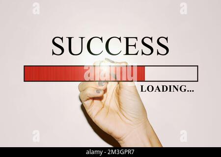 Hand einer Geschäftsfrau mit glitzernden Nägeln, die die Ladeleiste mit dem Text „Success“ zeigt Stockfoto