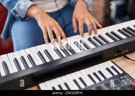 Junger nicht-binärer Musiker, der Klavier-Keyboard im Musikstudio spielt Stockfoto