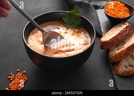 Der Mann isst Linsensuppe. Ein Löffel Linsensuppe Stockfoto
