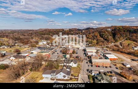 Panoramablick aus der Vogelperspektive auf einen kleinen südlichen Stadtplatz mit Whiskey-Fasshäusern auf dem Hügel und Herbstfarben im Lynchburg, Tennessee USA. Stockfoto